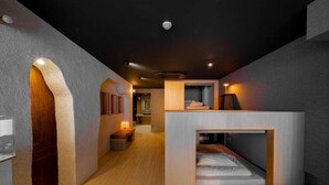A modern interior with a wooden floor, a built-in bench, and a small sleeping area with a mattress.