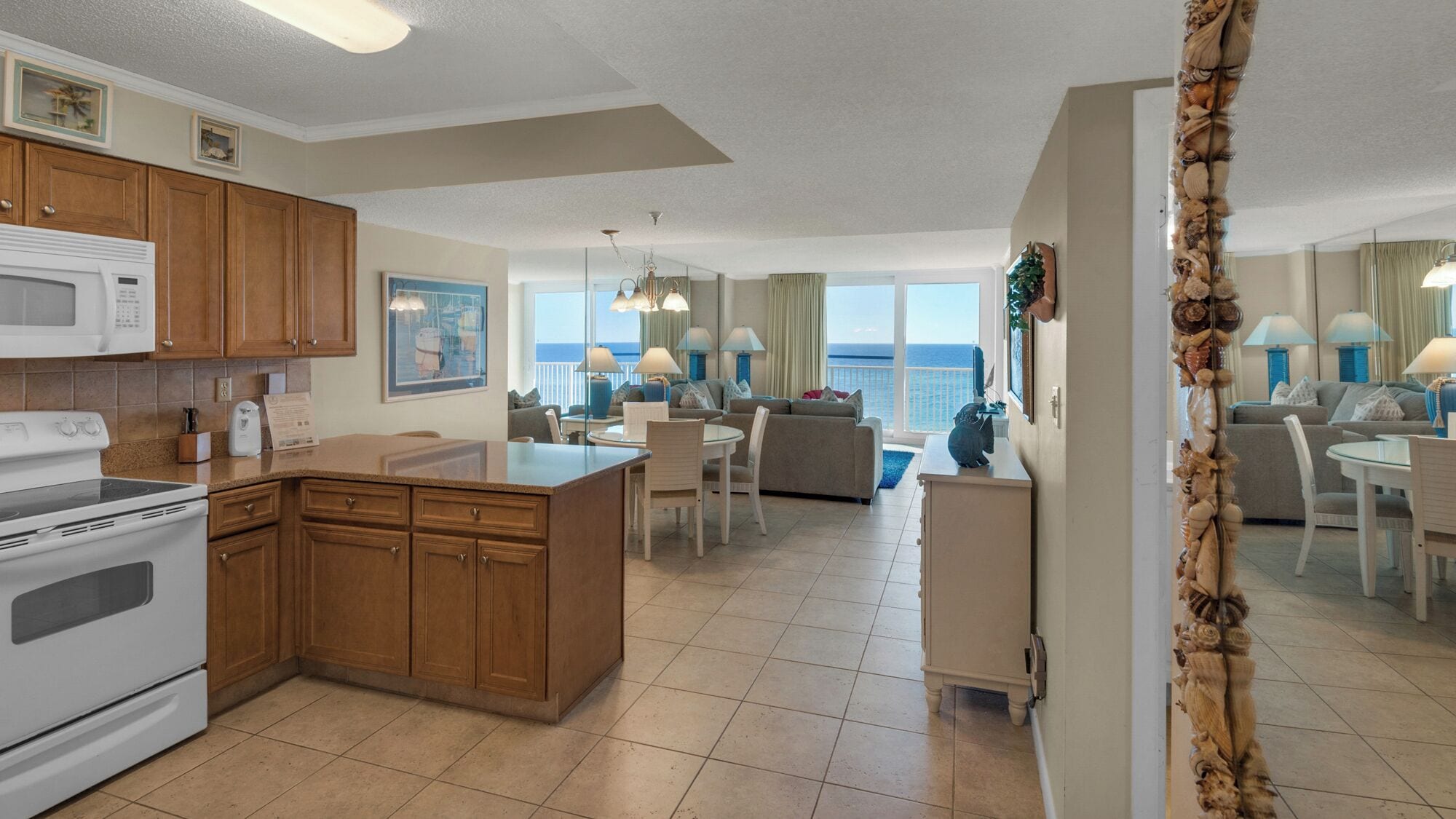 A spacious kitchen with wooden cabinets, a white stove, and a dining area with a view of the ocean.