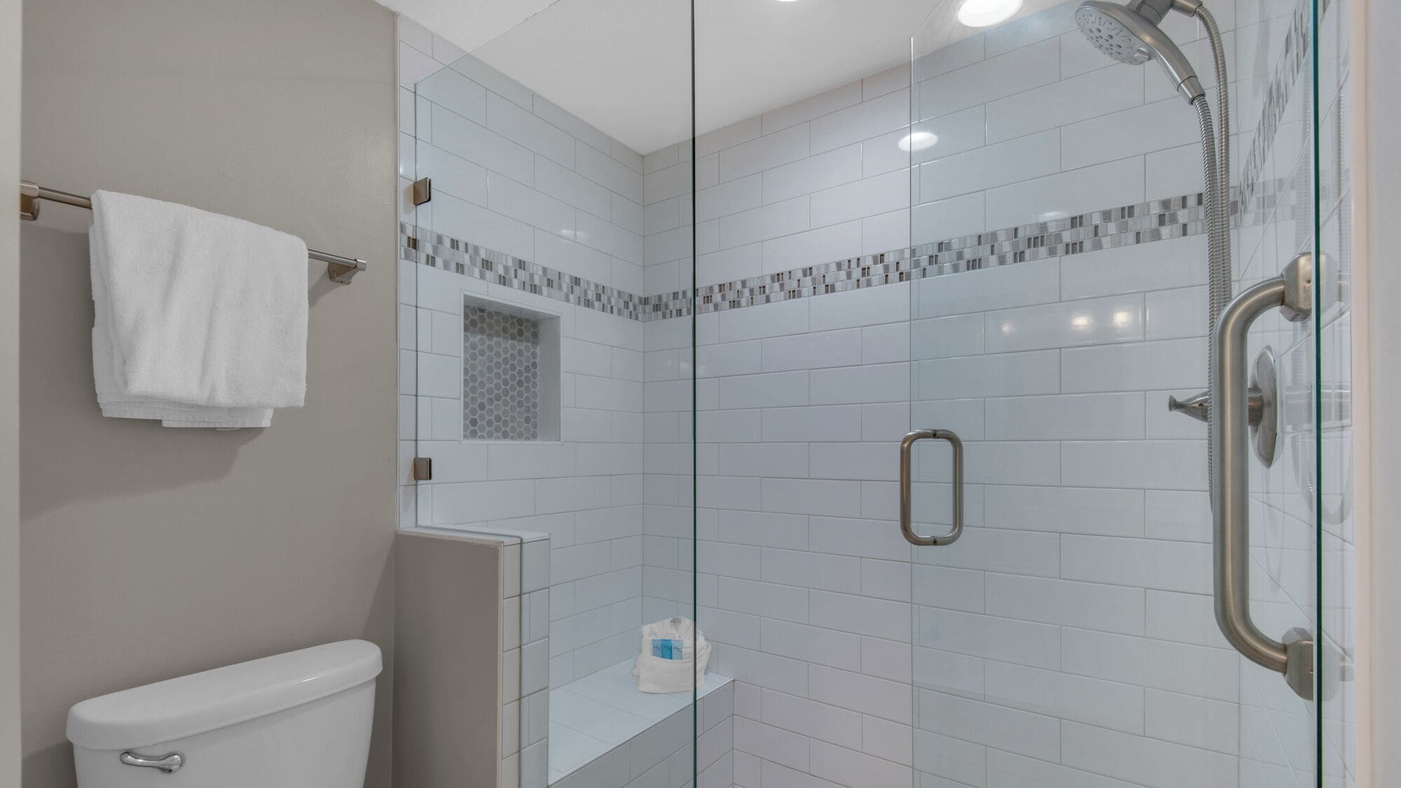Une salle de bain moderne avec une douche à parois de verre, des carreaux blancs et des toilettes.