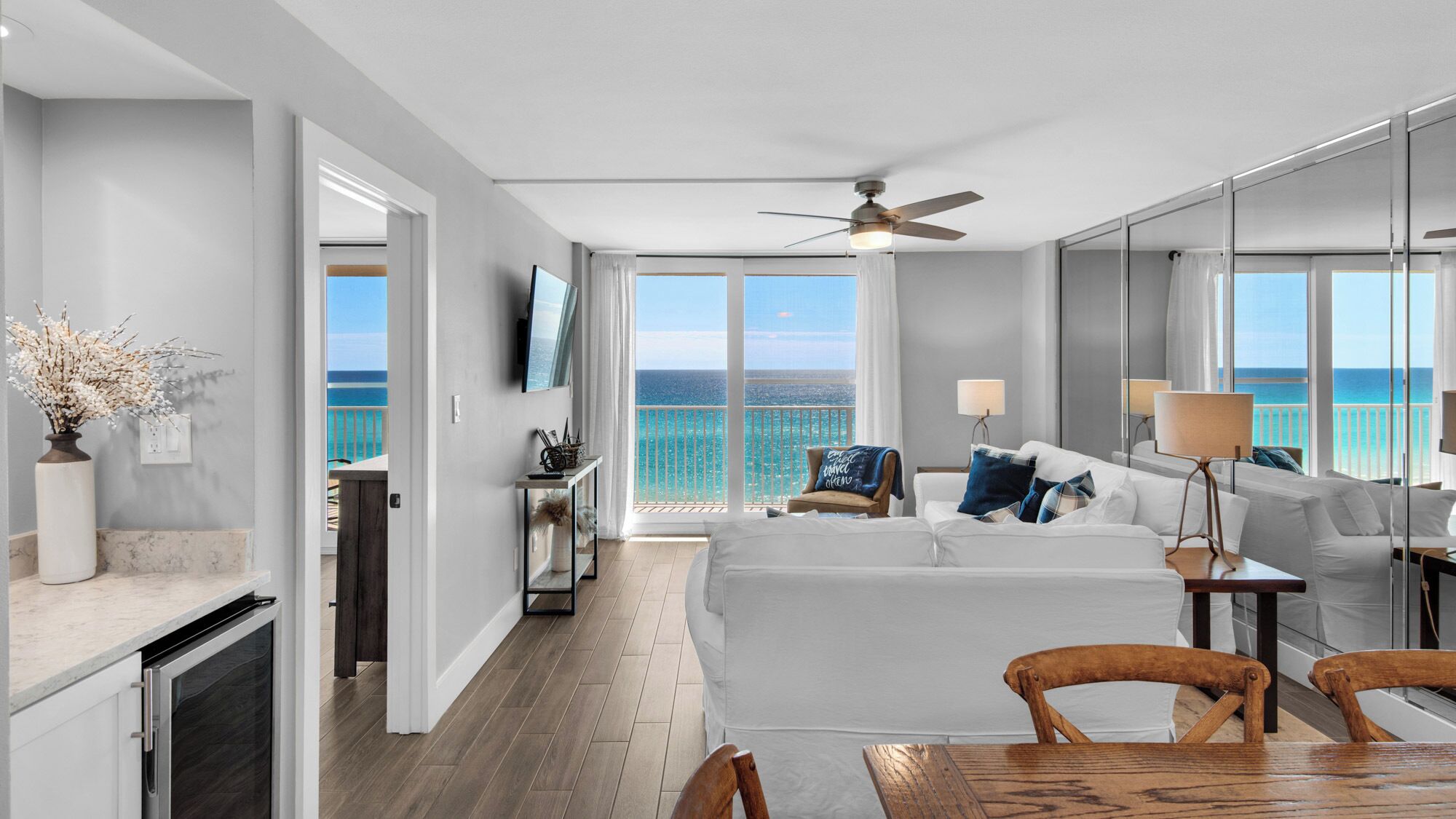 A modern hotel room with a balcony, a dining area, and a view of the ocean.