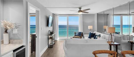 A modern hotel room with a balcony, a dining area, and a view of the ocean.