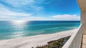 Vista a la playa desde un balcón, con cielos despejados y mar tranquilo.