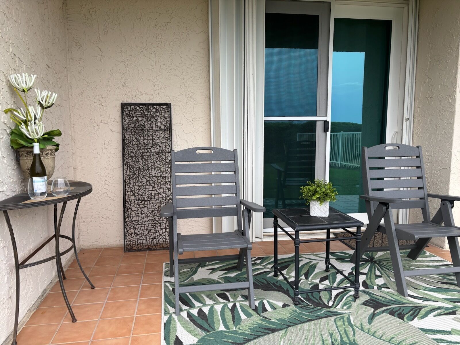 Ein Balkon mit zwei Stühlen, einem kleinen Tisch, einem Blumentopf und einer Zierplatte.