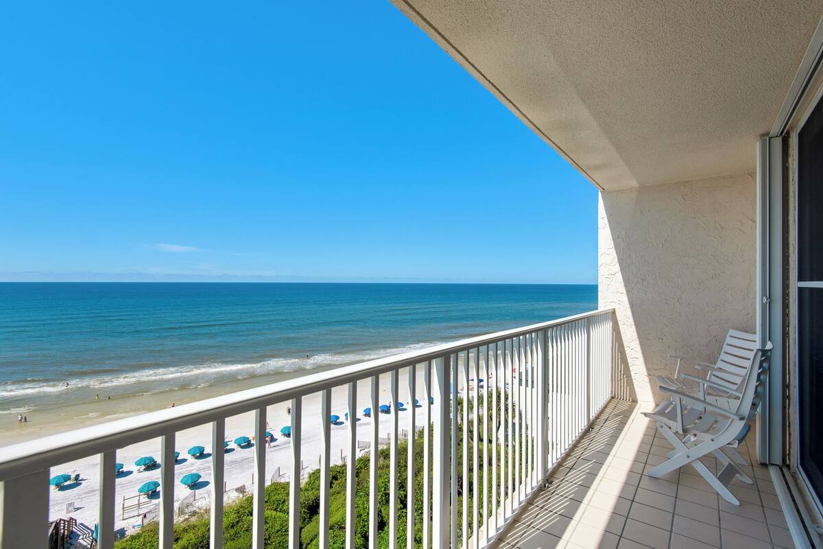 A balcony with a view of the beach and ocean.