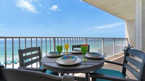 A balcony with a table set for two, overlooking the ocean.