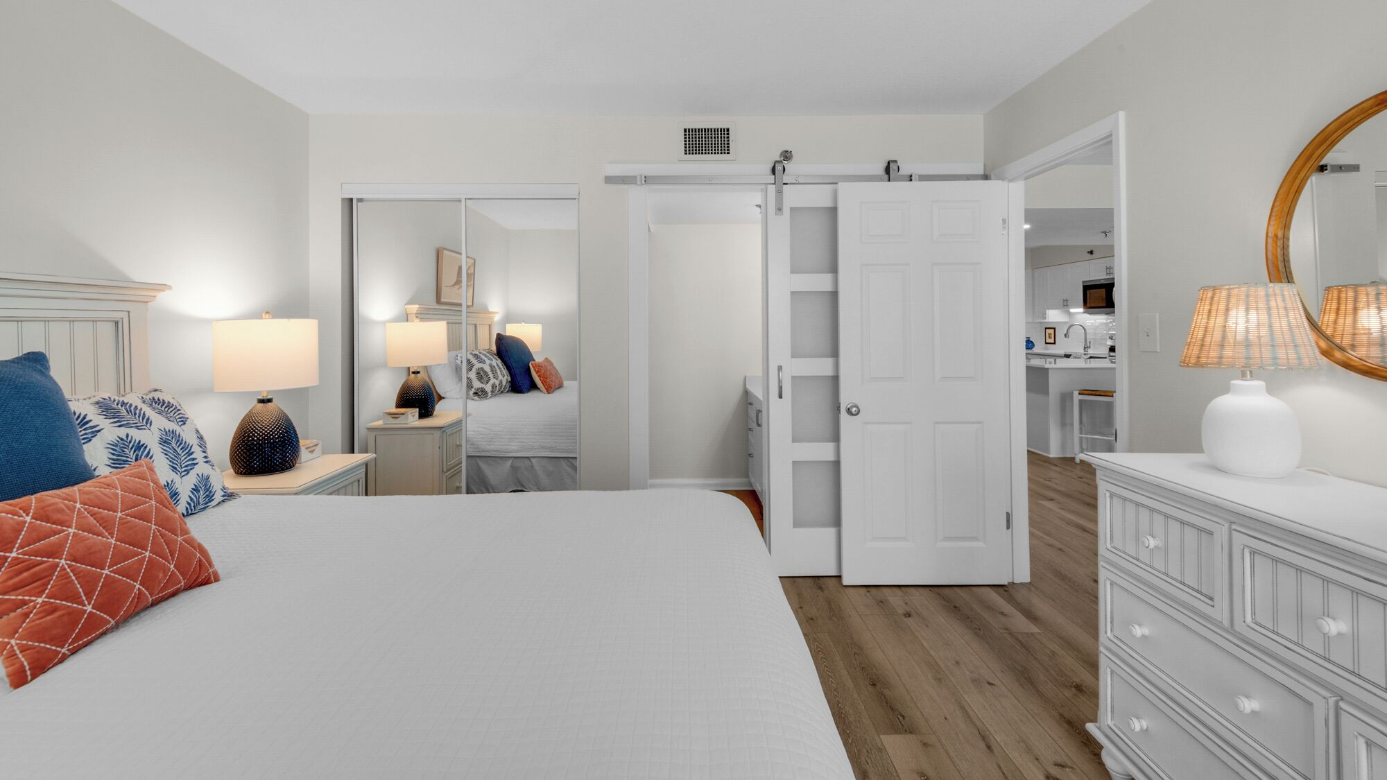 A bedroom with a bed, bedside tables, a wardrobe, and a mirror.
