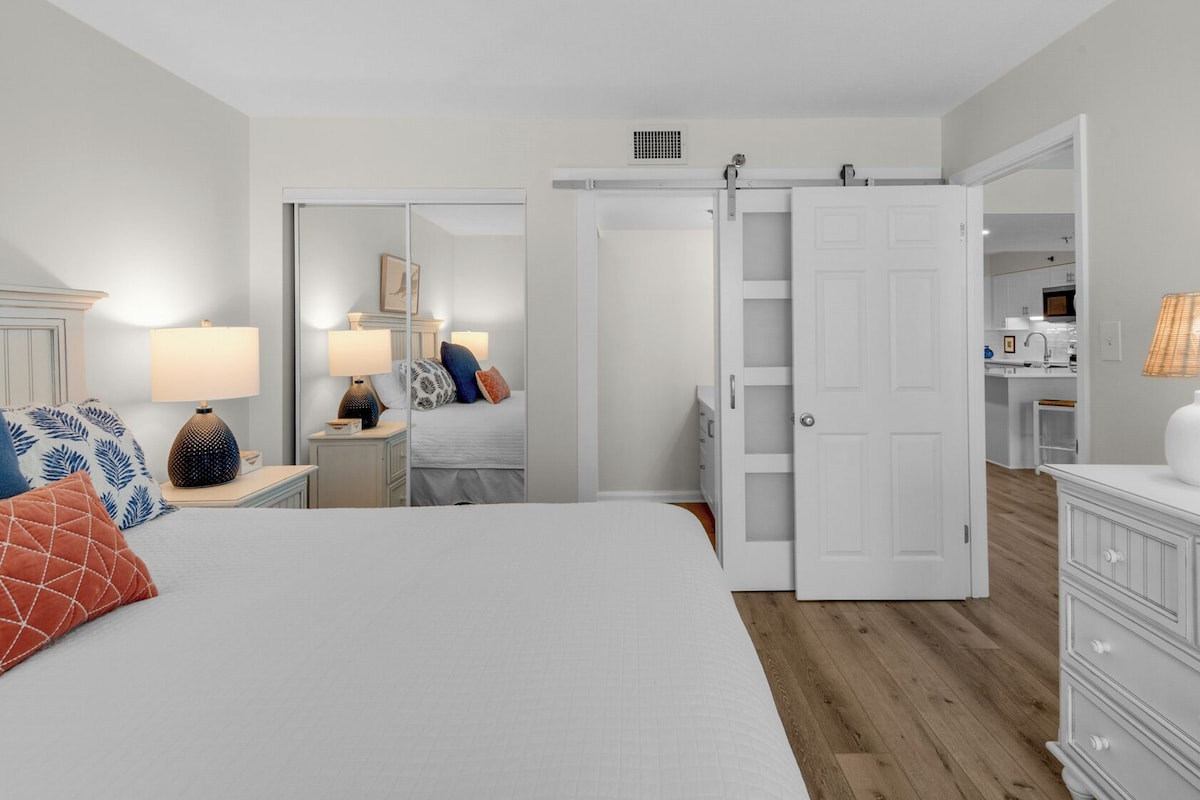 Un dormitorio con cama, mesitas de noche, armario y espejo.