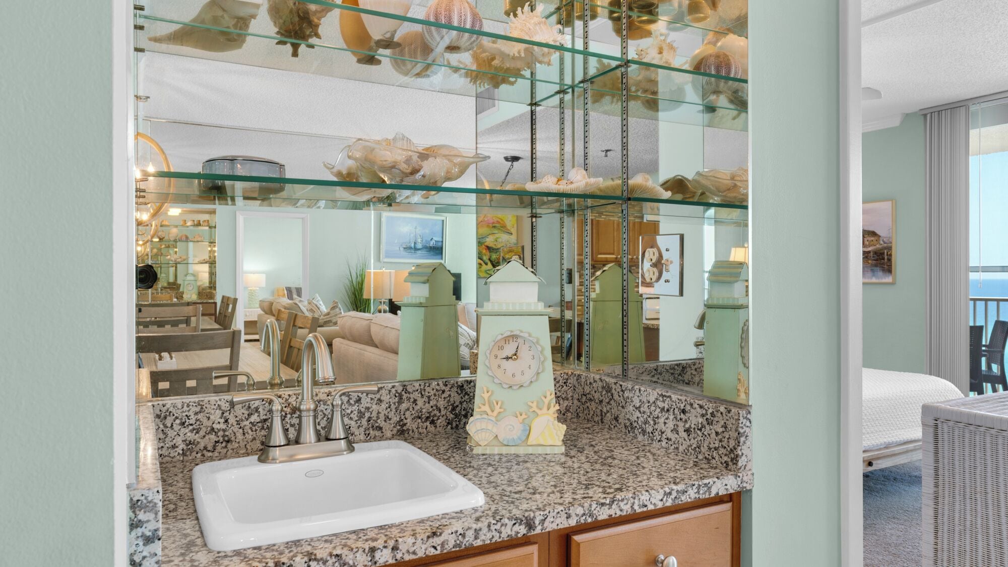 Un bagno con un piano in granito, un lavandino bianco e un orologio decorativo.