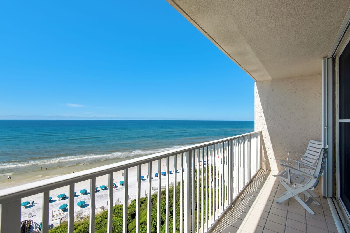 A balcony with a view of the beach and ocean.