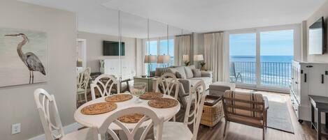Una sala de estar moderna con comedor, ventanas amplias y vista al océano.