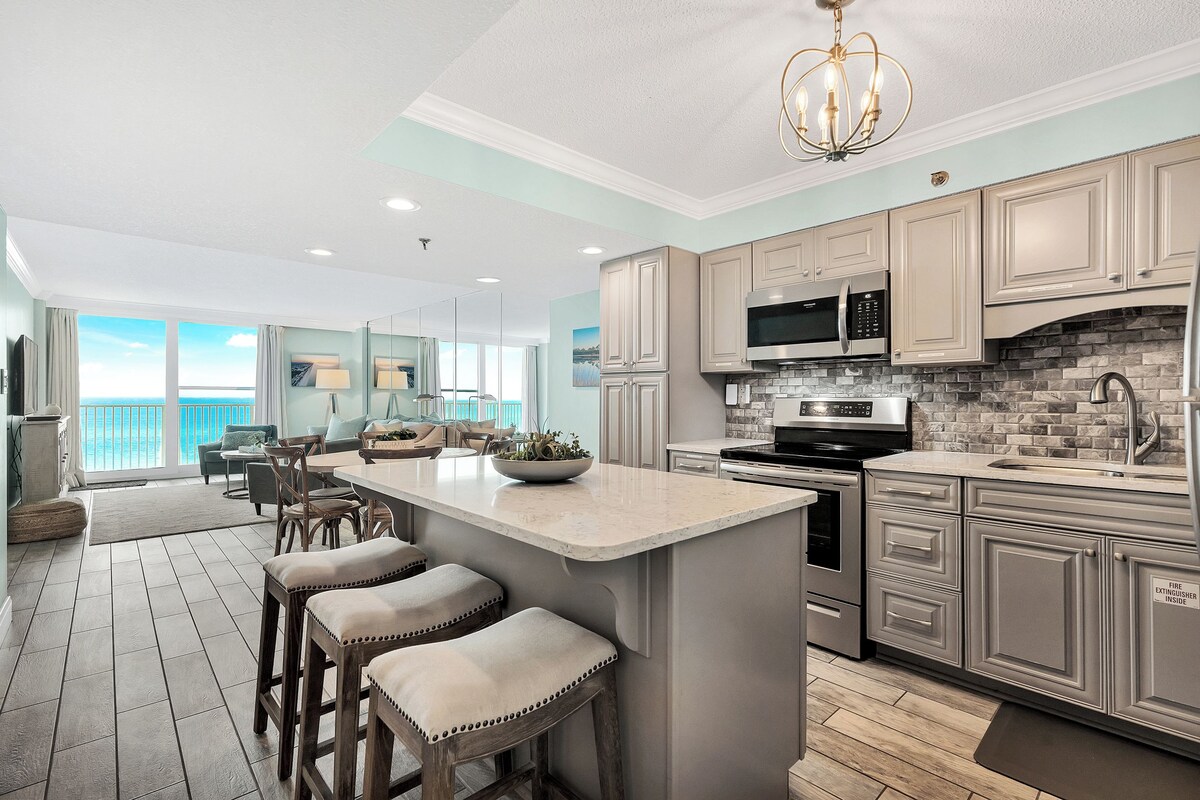 A modern kitchen with a large island, built-in appliances, and a view to the outside.