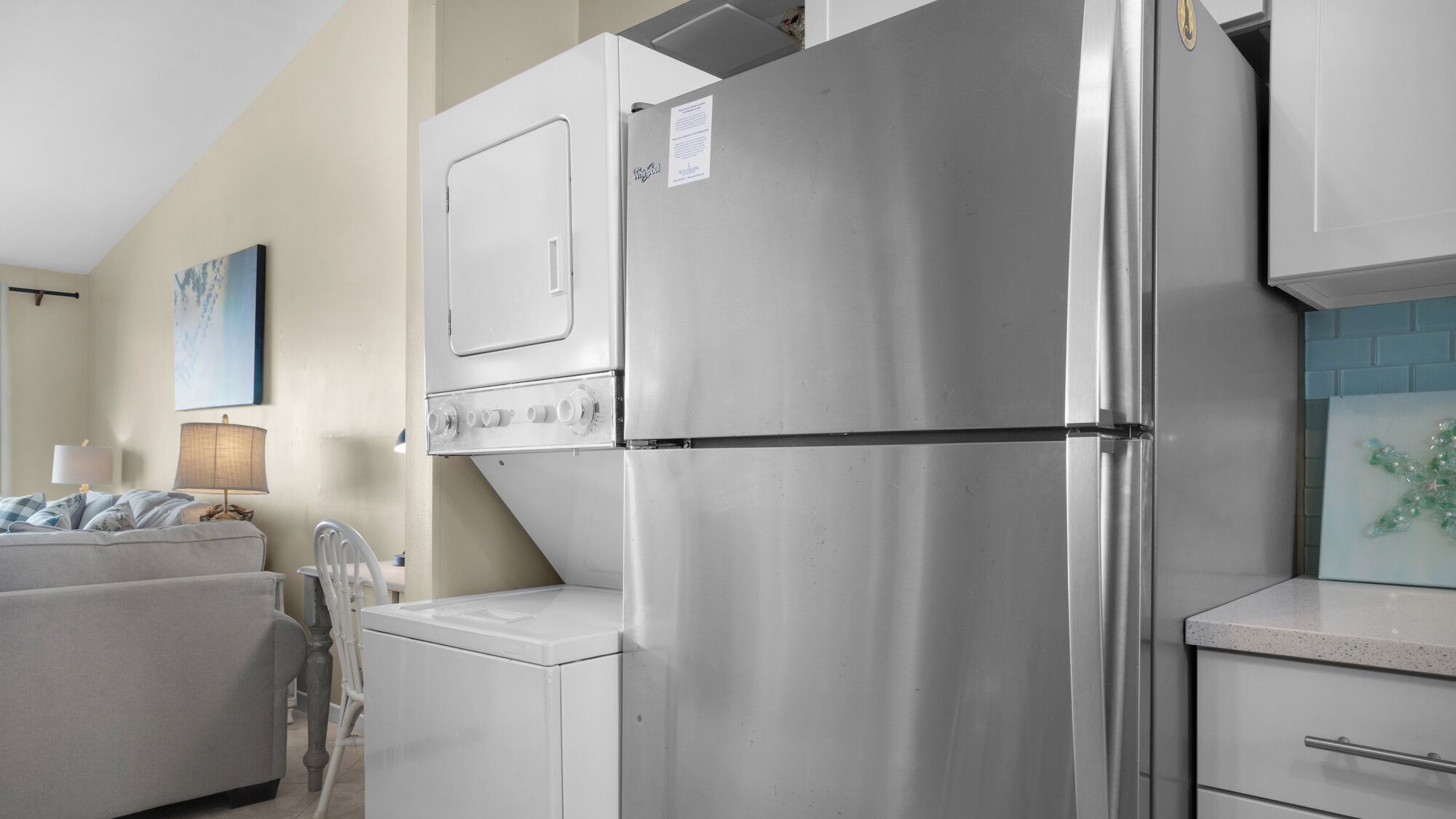 A compact kitchen with a stainless steel refrigerator, a built-in oven, and a washing machine.