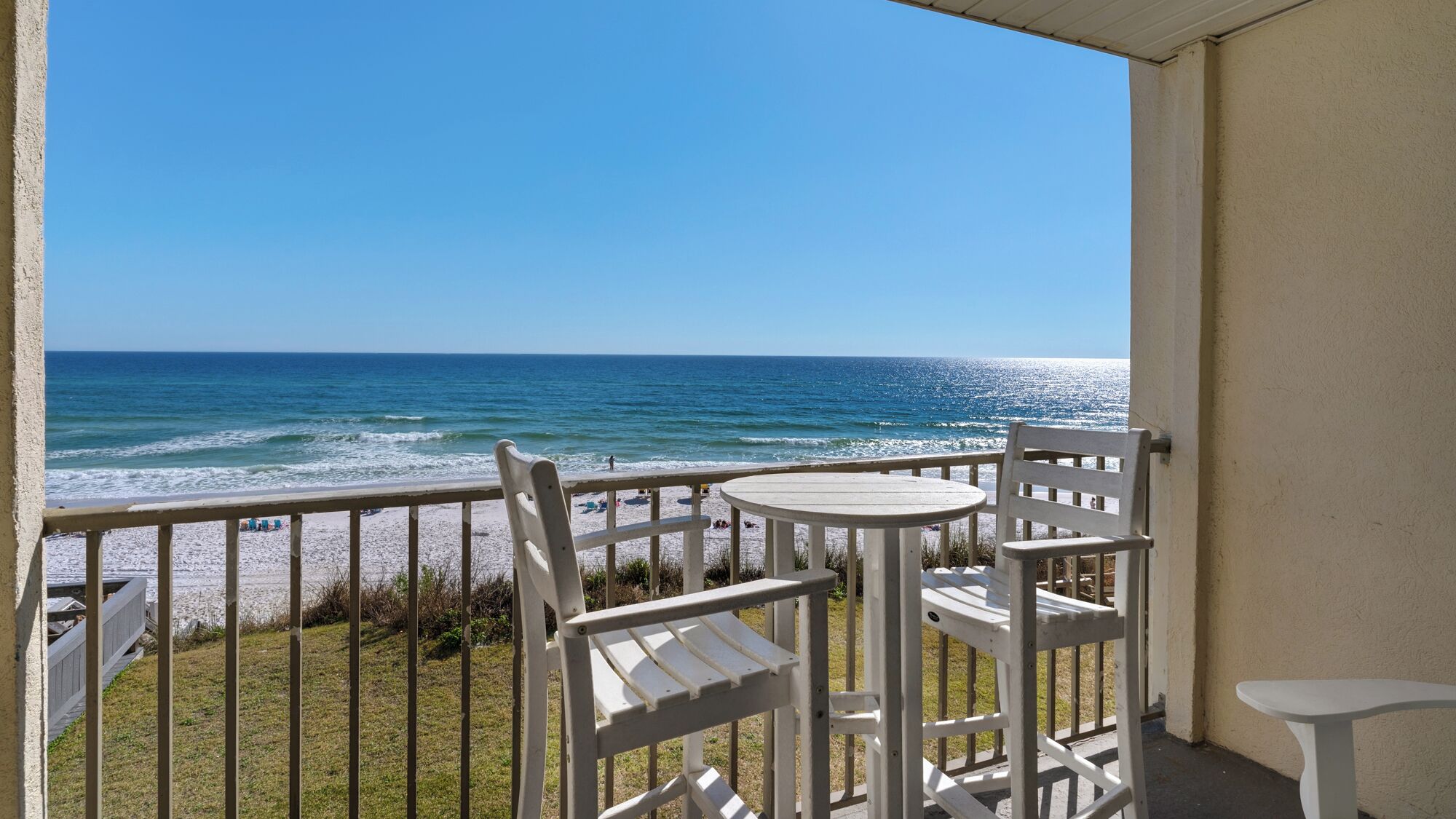 A balcony with a view of the ocean, featuring a round table and two chairs.
