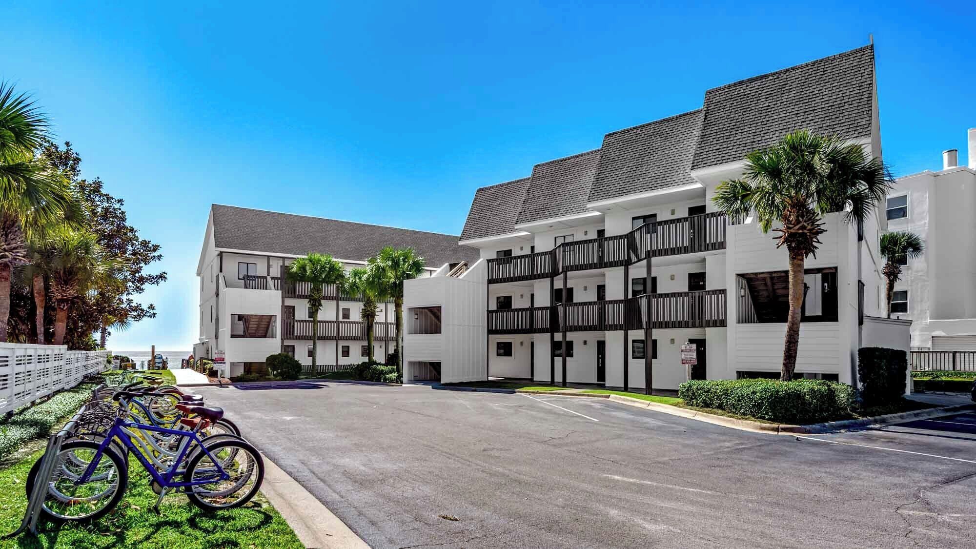 A multi-story hotel with a modern design, featuring balconies and a parking area with bicycles.