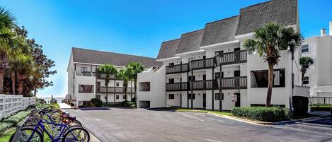 A multi-story hotel with a modern design, featuring balconies and a parking area with bicycles.