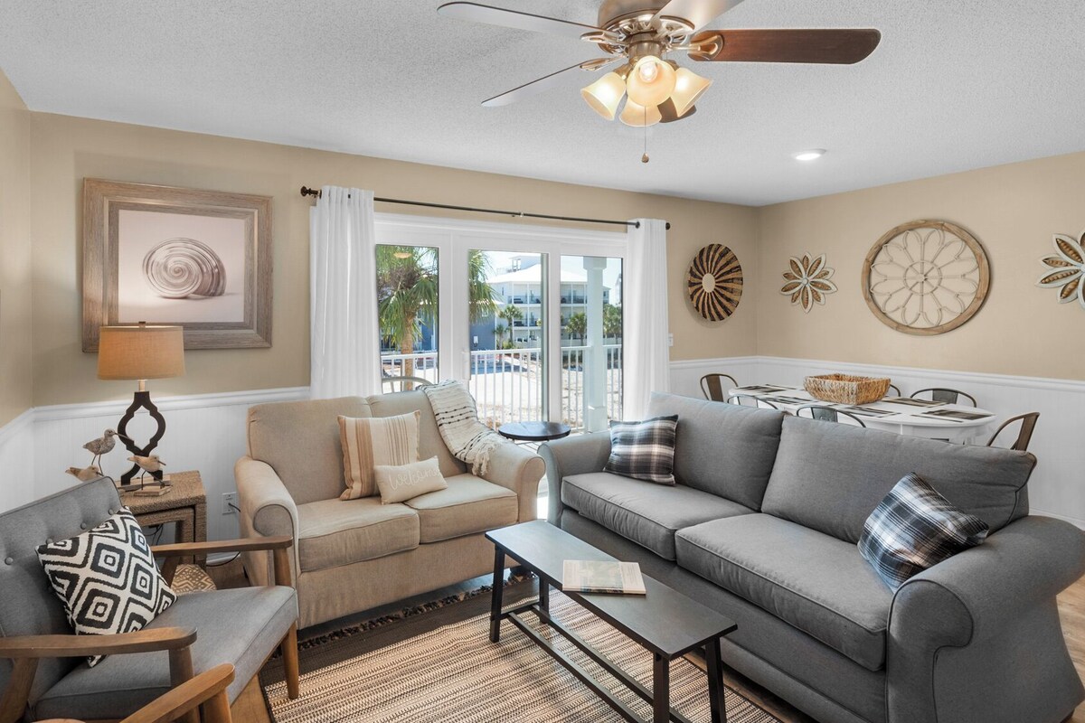 A living room with a sofa, armchair, coffee table, and a dining area with a table and chairs.