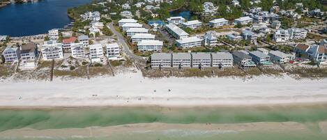 An aerial view of a coastal residential area with beachfront properties, a beach, and a body of water.