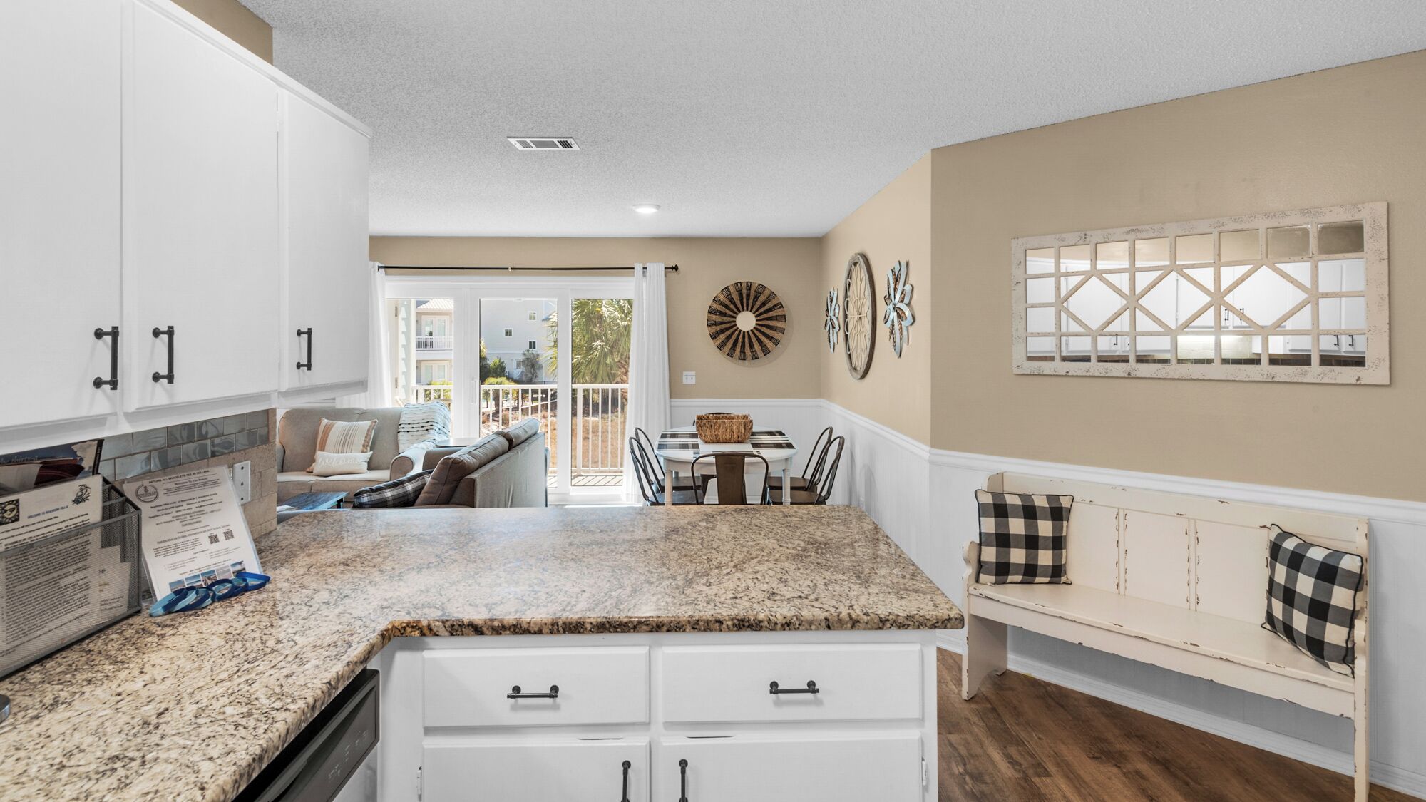 A kitchen with white cabinets, a granite countertop, and a dining area with a table and chairs.