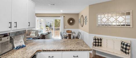 A kitchen with white cabinets, a granite countertop, and a dining area with a table and chairs.