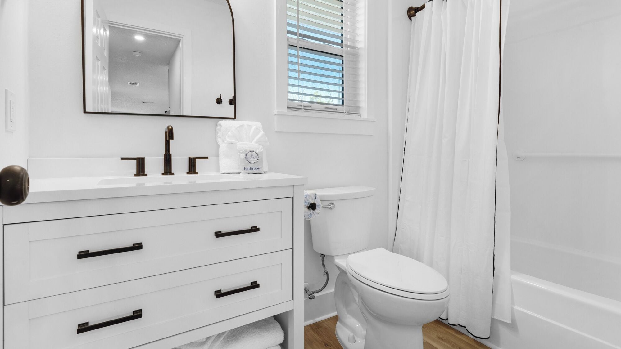 A modern bathroom with a white vanity, a toilet, and a shower area.
