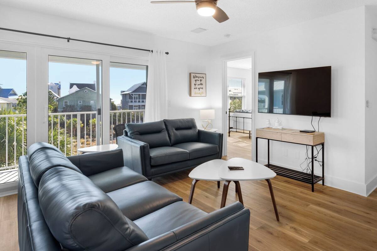 Un salon moderne avec un canapé d’angle, une table basse et un téléviseur fixé au mur.