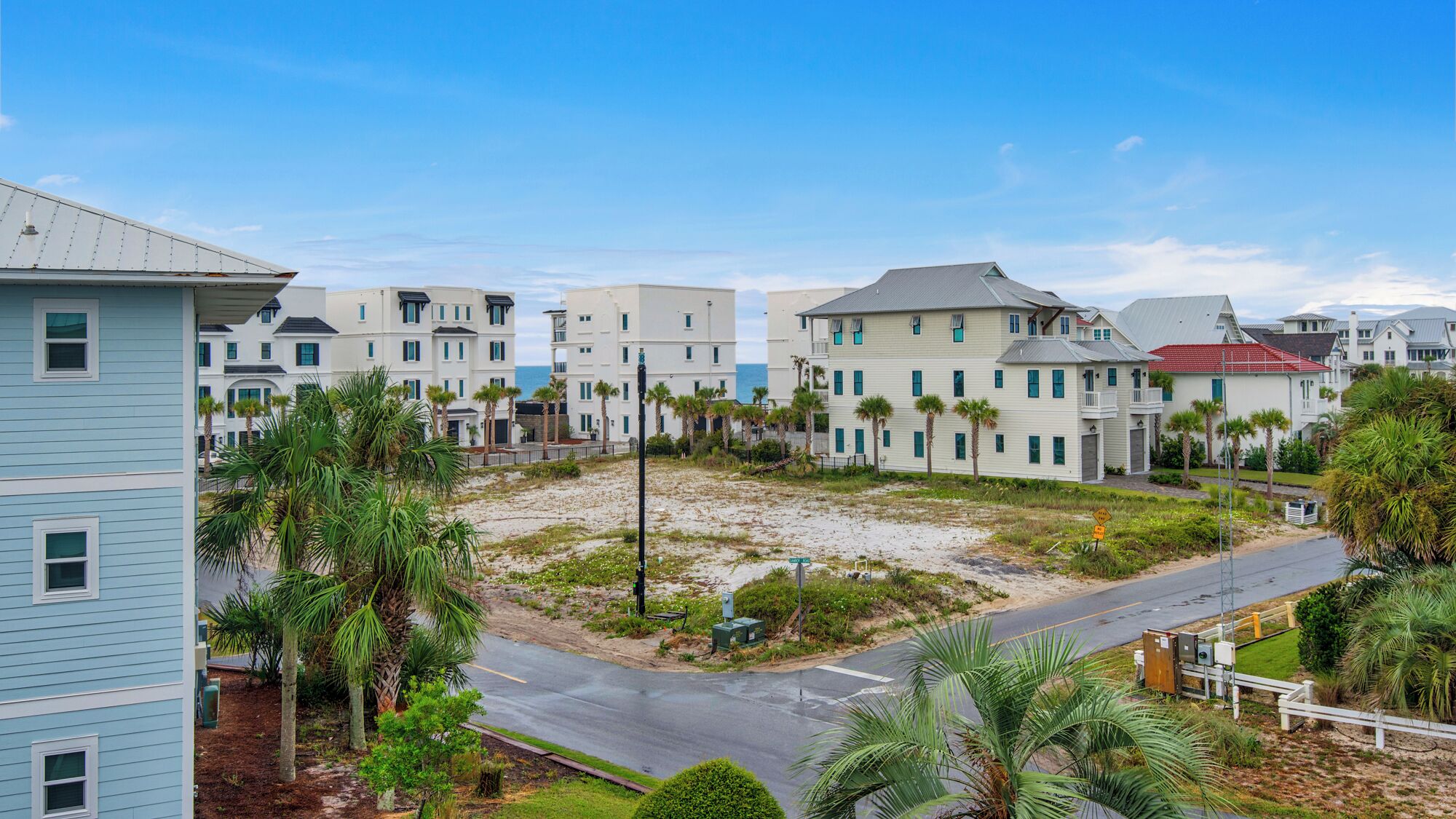 A coastal residential area with multi-story buildings, a sandy beach, and a road.