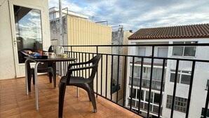 A balcony with a table and chairs, a view of neighboring buildings, and a tiled floor. - Ideal Apartment in the Center of Roses – INMO ASESORÍA EL AKEL (Roses)