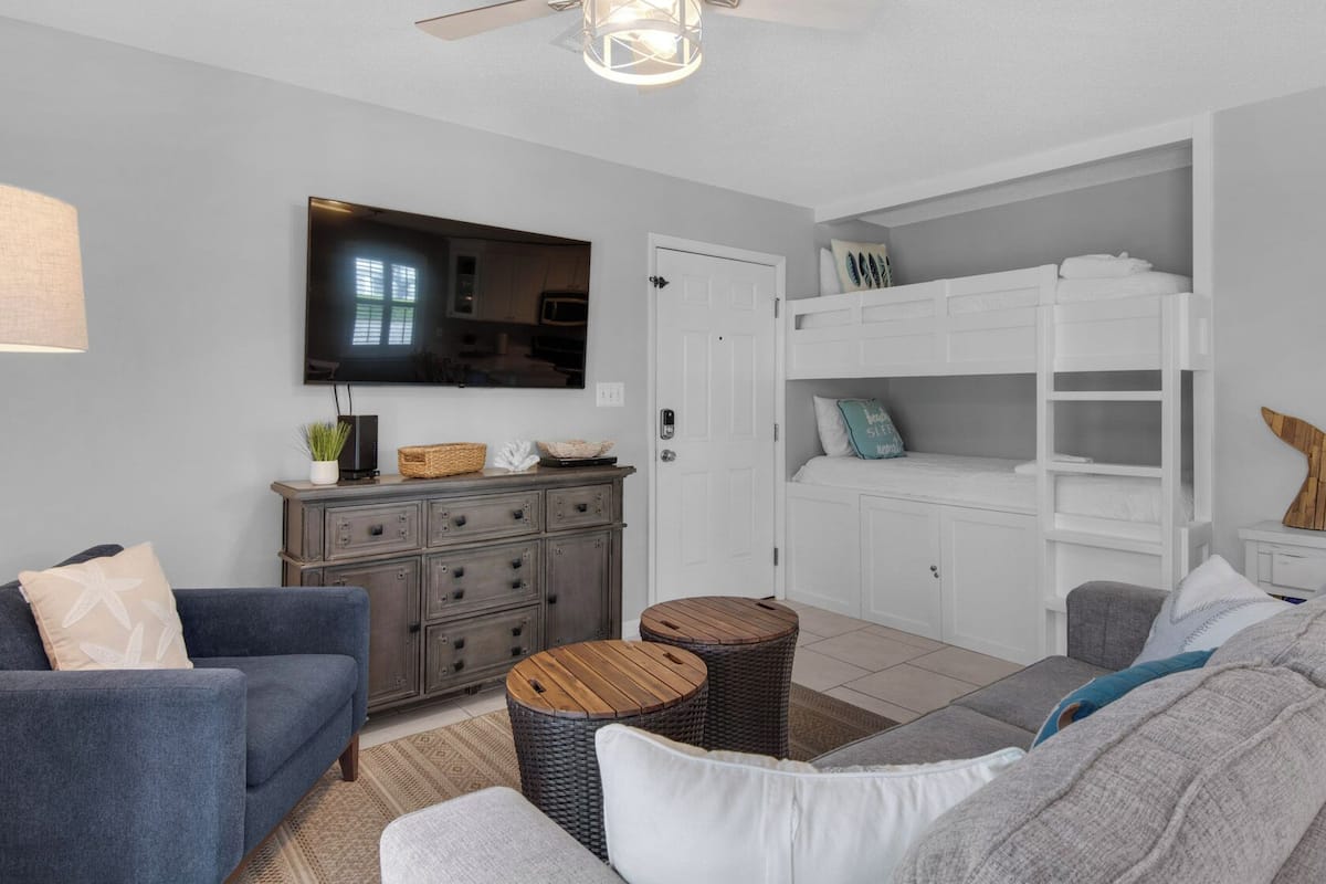 A living room with a TV, sofa, and a white built-in bench with shelves.