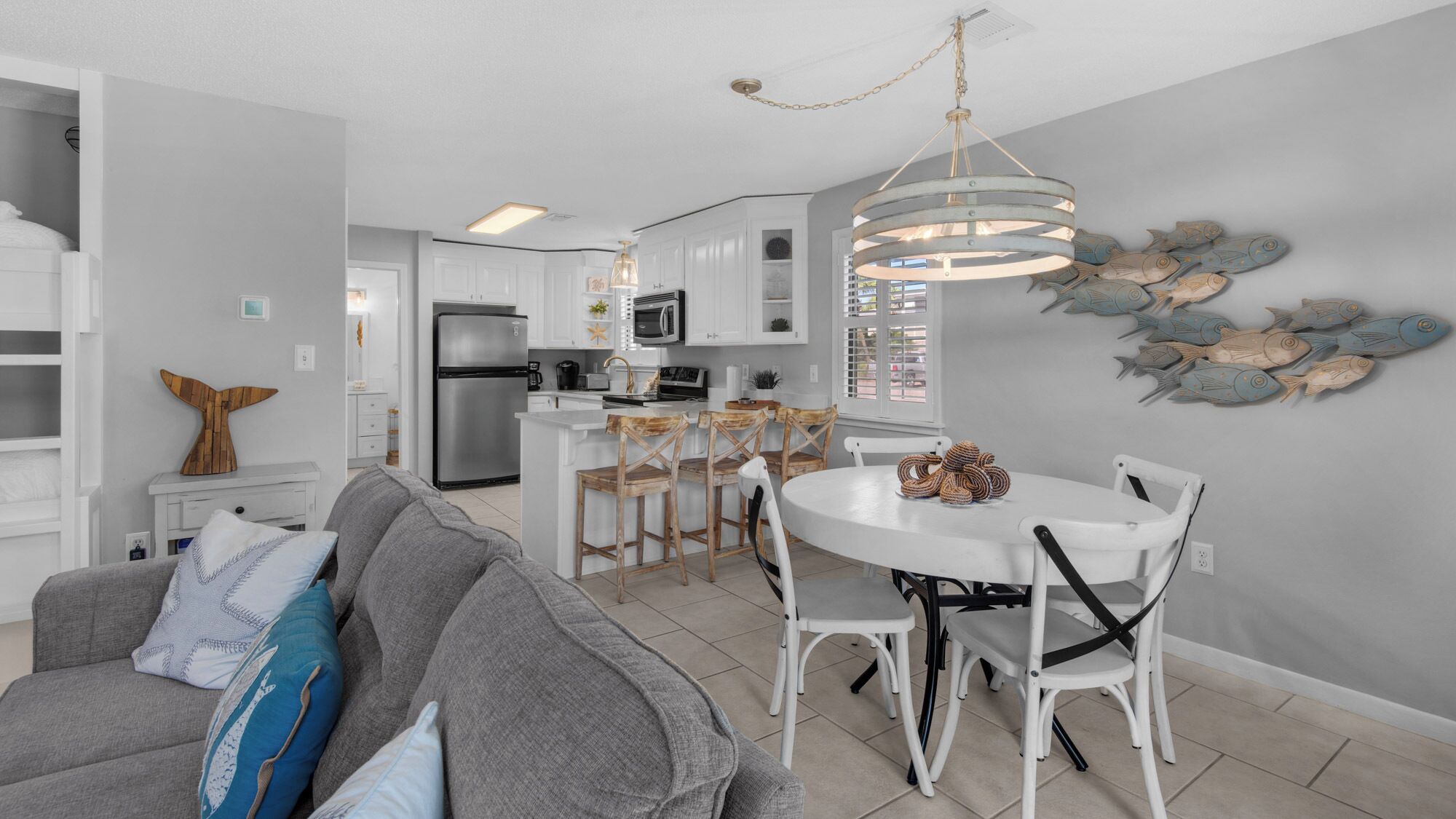 A modern kitchen with white cabinets, a stainless steel refrigerator, and a dining area with a white table and chairs.