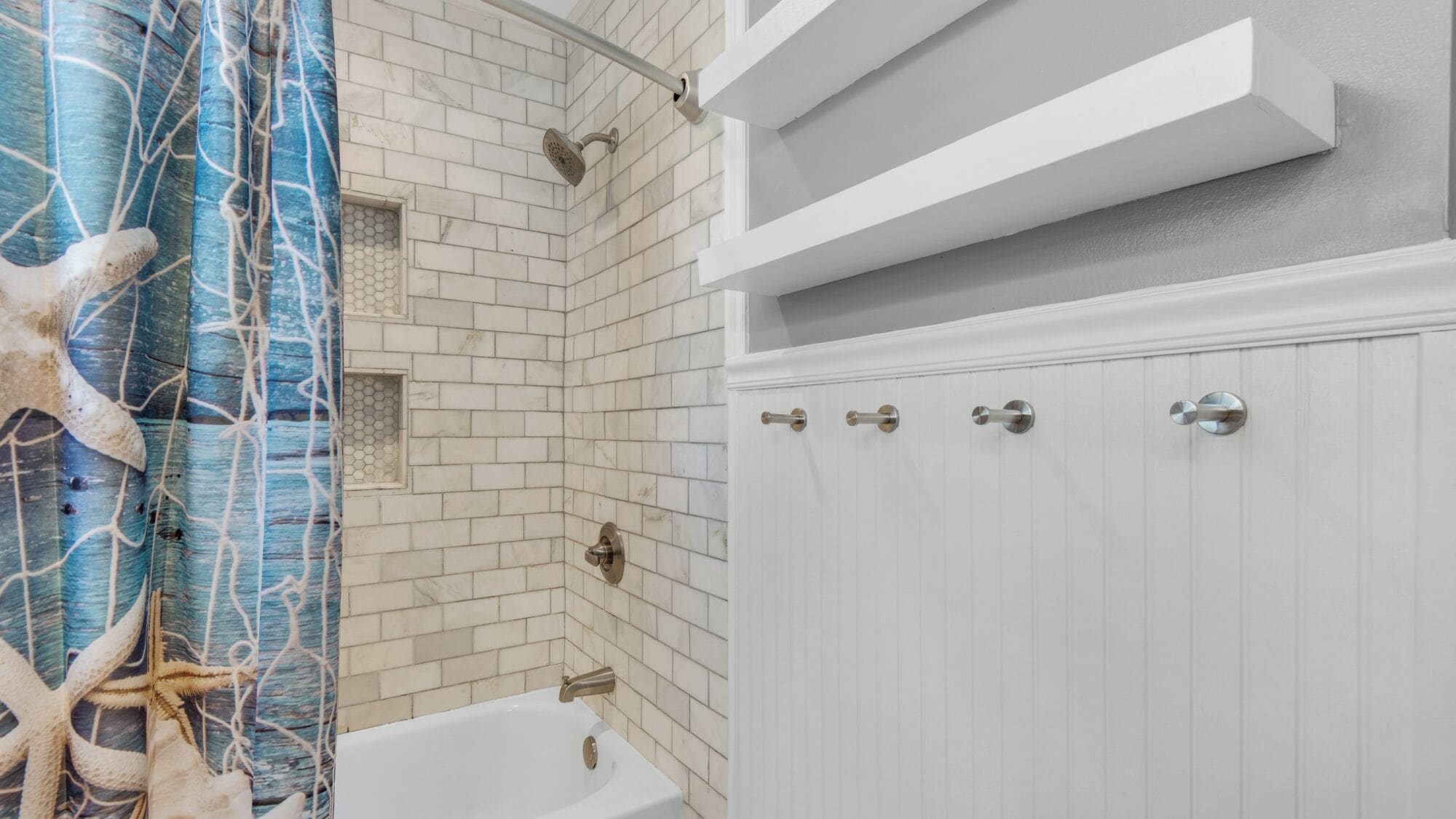 A bathroom with white subway tiles, a bathtub, and a shower with a rain showerhead.