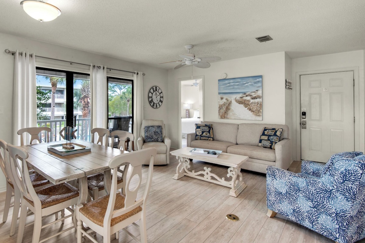 A living room with a dining area, a sofa, a coffee table, and a chair with a patterned cushion.