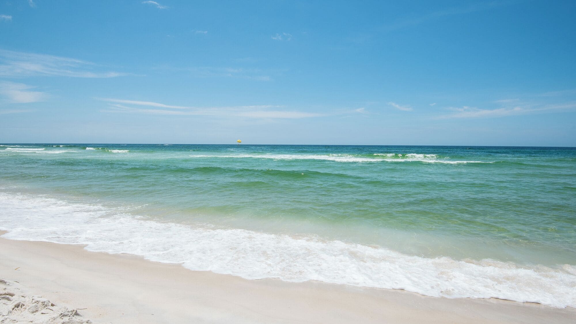 A beach with clear water and a sandy shore.