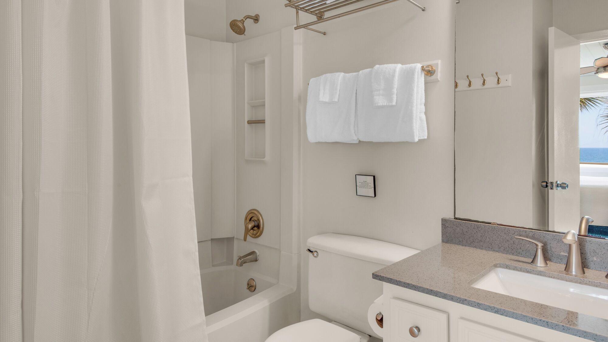 A bathroom with a bathtub, toilet, sink, and a towel rack with towels.