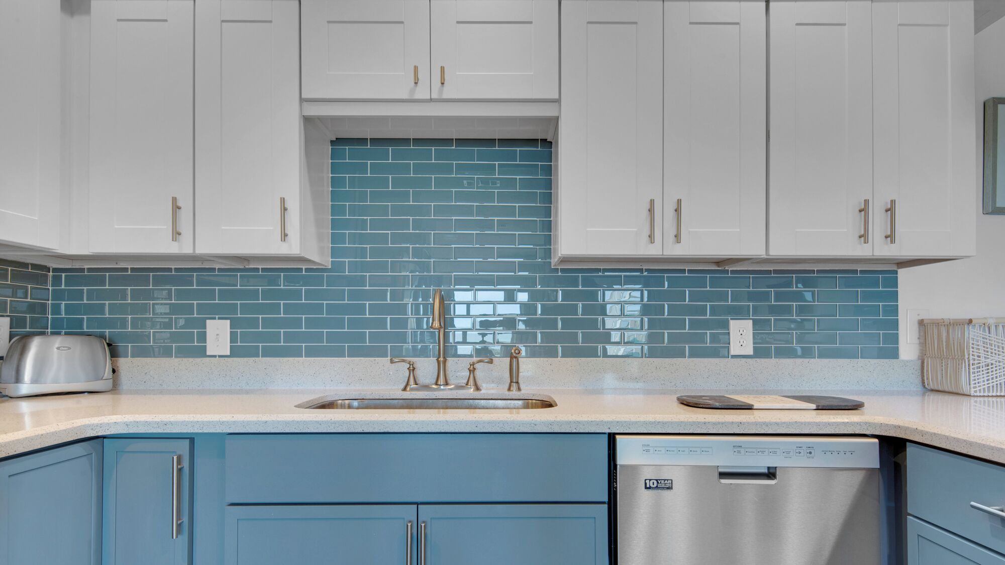 A kitchen with white cabinets, a blue backsplash, and a stainless steel dishwasher.