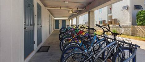 A covered bike parking area with multiple bicycles and a concrete floor.