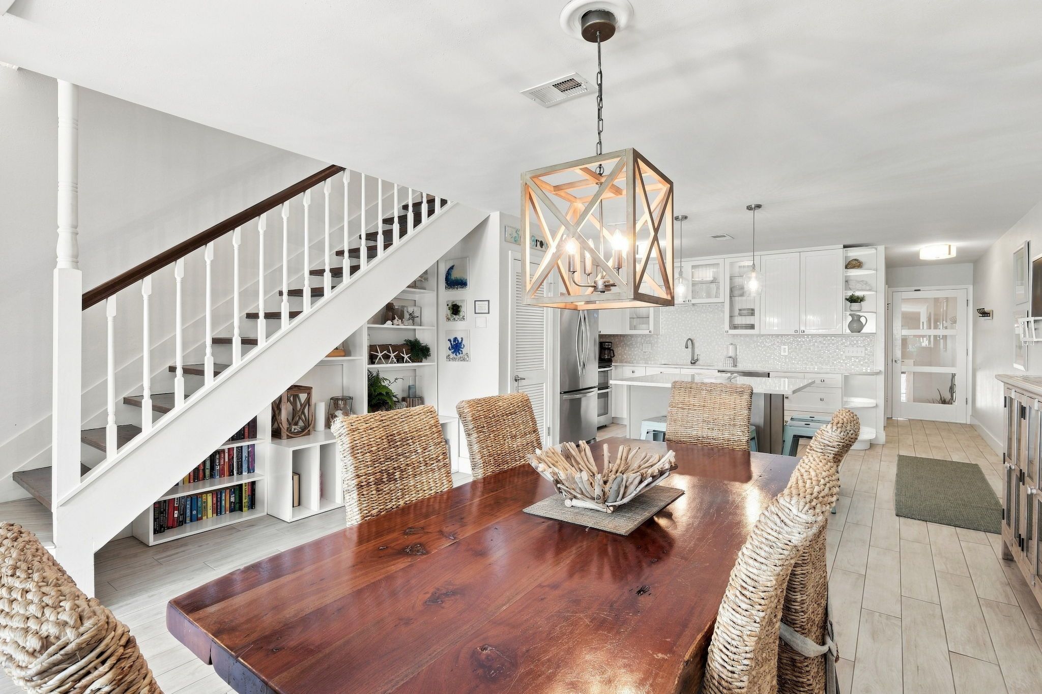 A spacious dining area with a wooden table, woven chairs, and a modern pendant light.