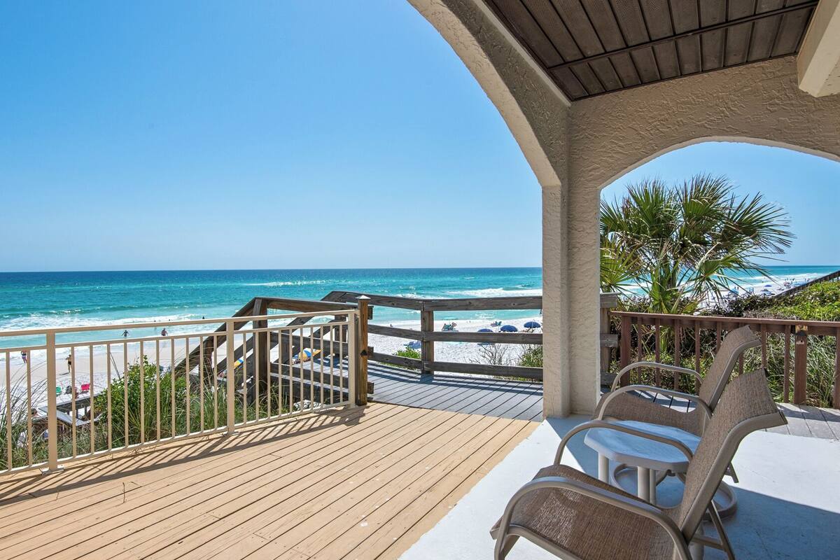 A wooden deck with a view of the beach and ocean.