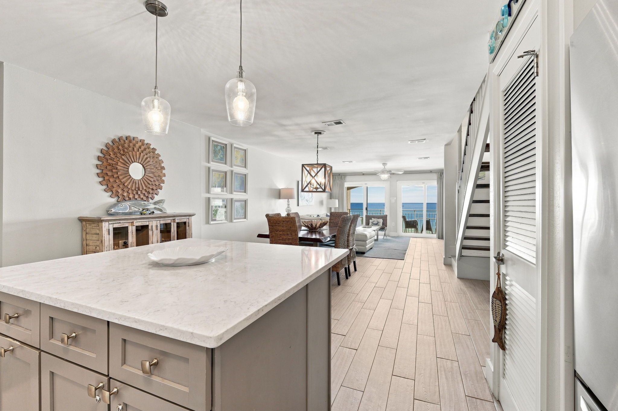 A spacious kitchen with a large island, pendant lights, and a view to the outside.
