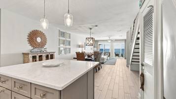 A spacious kitchen with a large island, pendant lights, and a view to the outside.