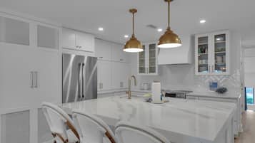A modern kitchen with white cabinetry, stainless steel appliances, and a marble island.