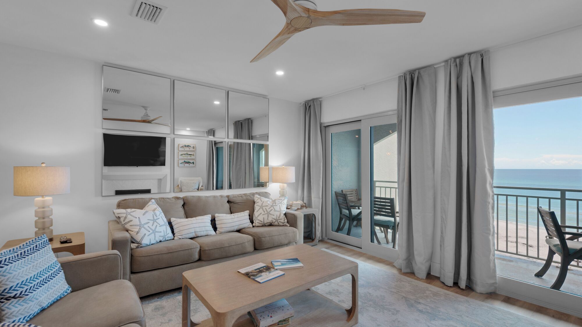 A modern living room with a sofa, coffee table, and a large window with a view of the ocean.