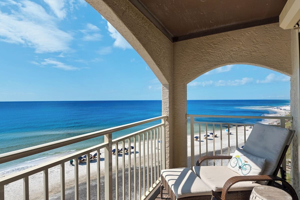 A balcony with a view of the beach and ocean.