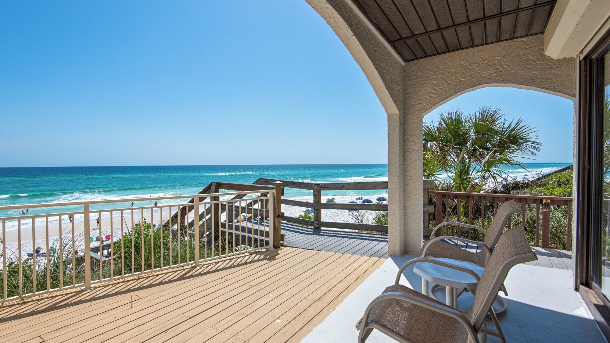 A wooden deck with a view of the beach and ocean.
