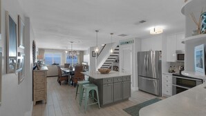 A modern kitchen with a central island, stainless steel appliances, and a view to the outside. - Dune Villas (Santa Rosa Beach)