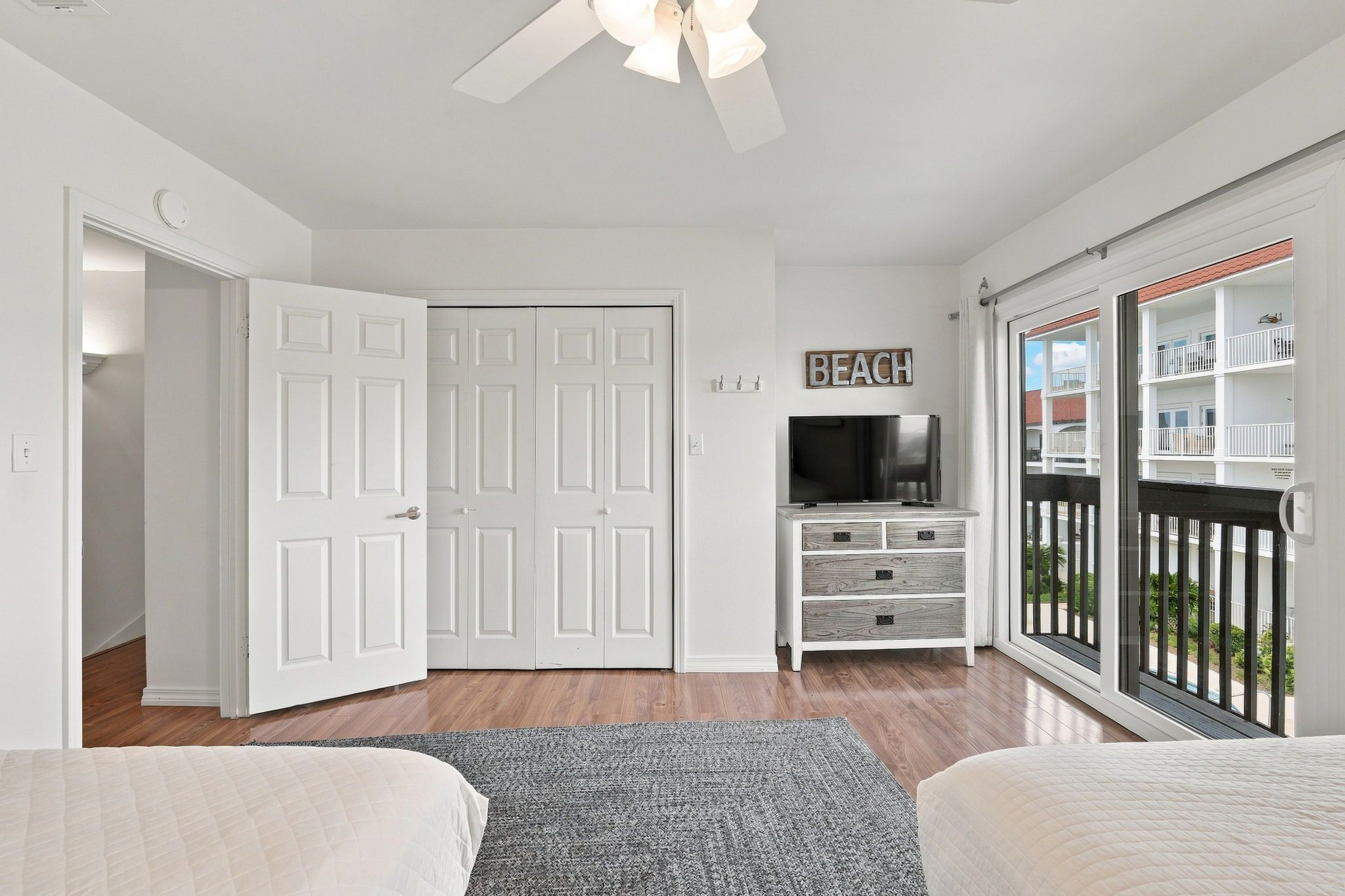 A bedroom with a TV, a closet, and a balcony with a view.
