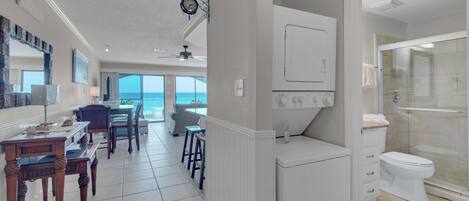 A hotel room with a balcony, a dining area, a kitchen, and a bathroom.