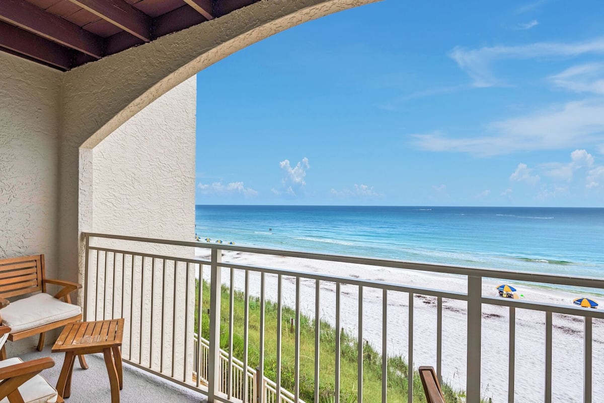 A balcony with a view of the beach and ocean.