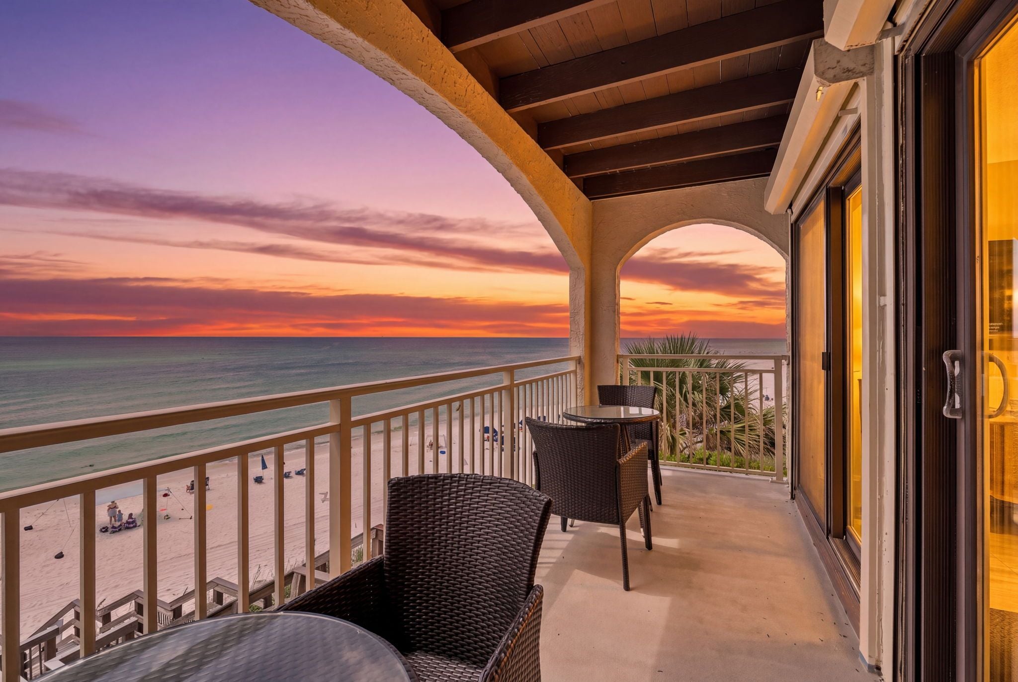 Un balcón con vista a la playa y al océano al atardecer.