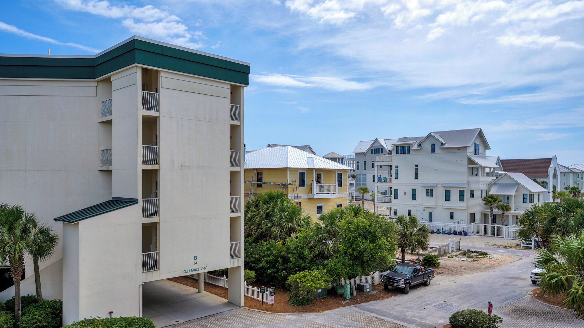 A multi-story residential building with balconies and a parking area.
