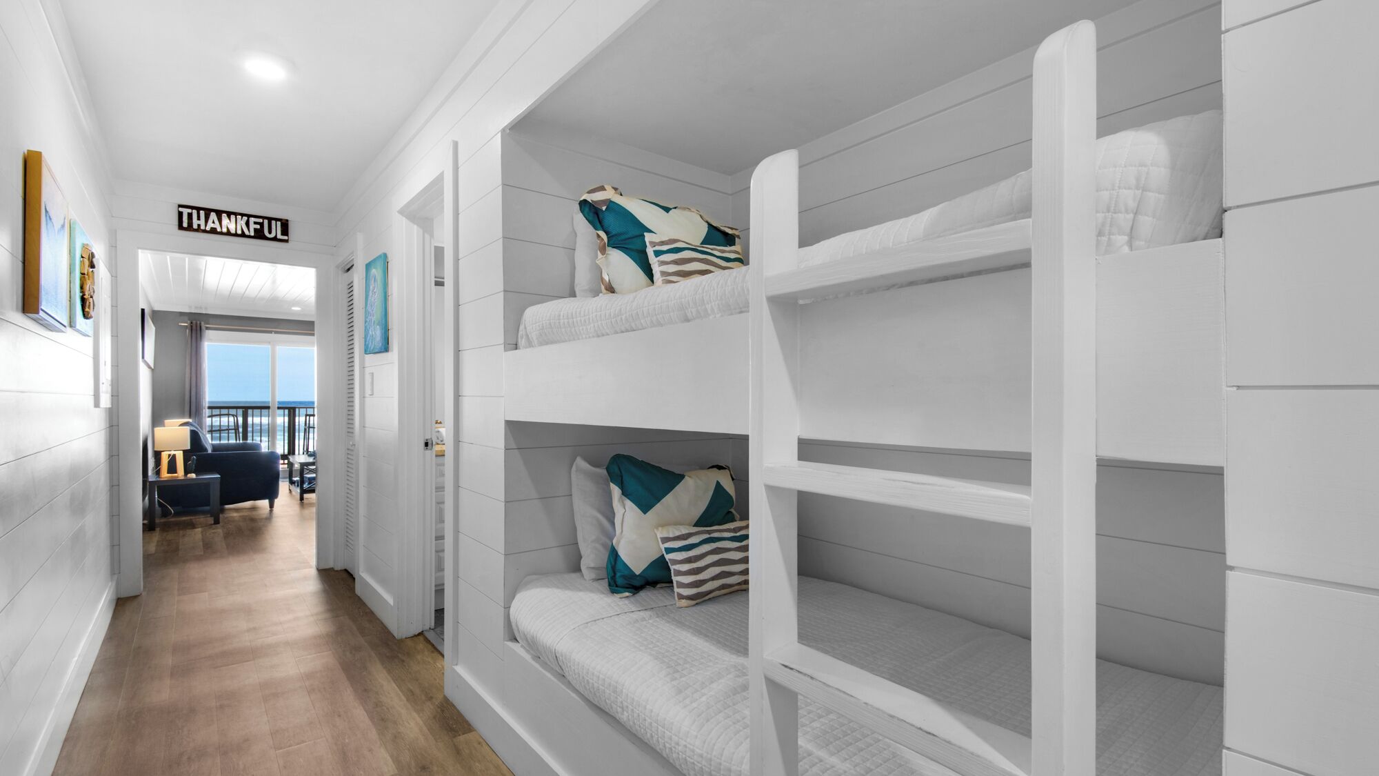 Ein Hotelzimmer mit Etagenbett, Blick auf das Meer und einem Schild mit der Aufschrift 'THANKFUL'.